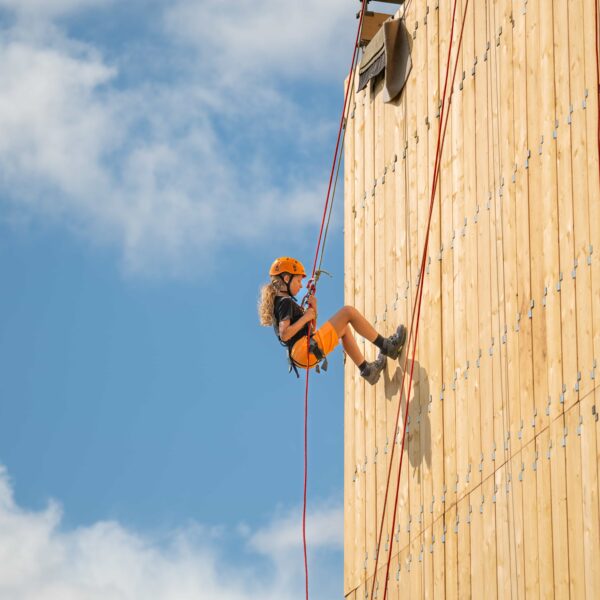 A girl abseils down a wall at Gone Wild festival