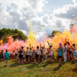 Participants throw powder paint in the air at the start of the colour run activity