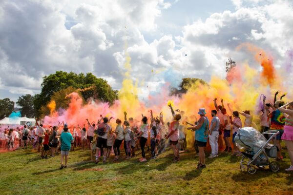 Participants throw powder paint in the air at the start of the colour run activity