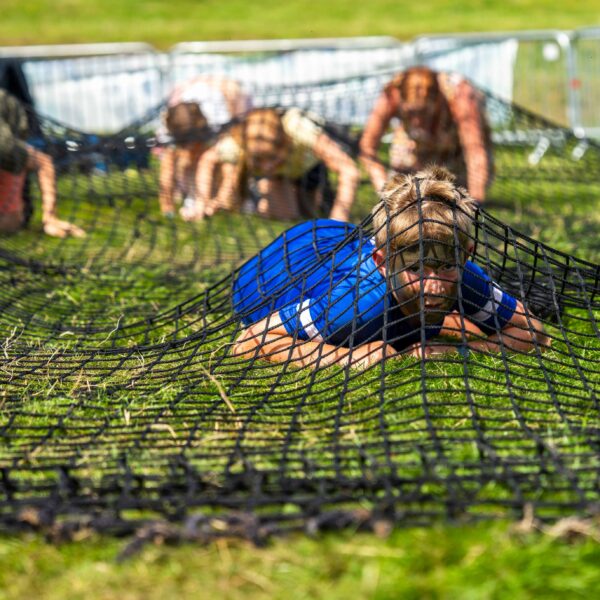 Children and adults crawl under a net in a n obstacle course