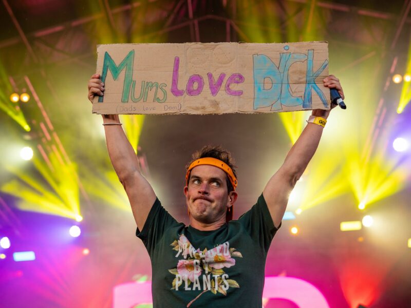 Dom from 'Dick and Dom' holds up a cardboard sign on stage